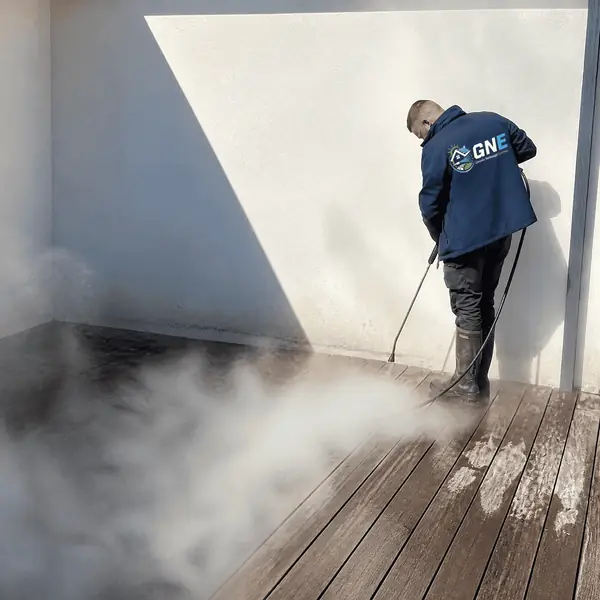Technicien GNE nettoyant une terrasse en bois à la vapeur
